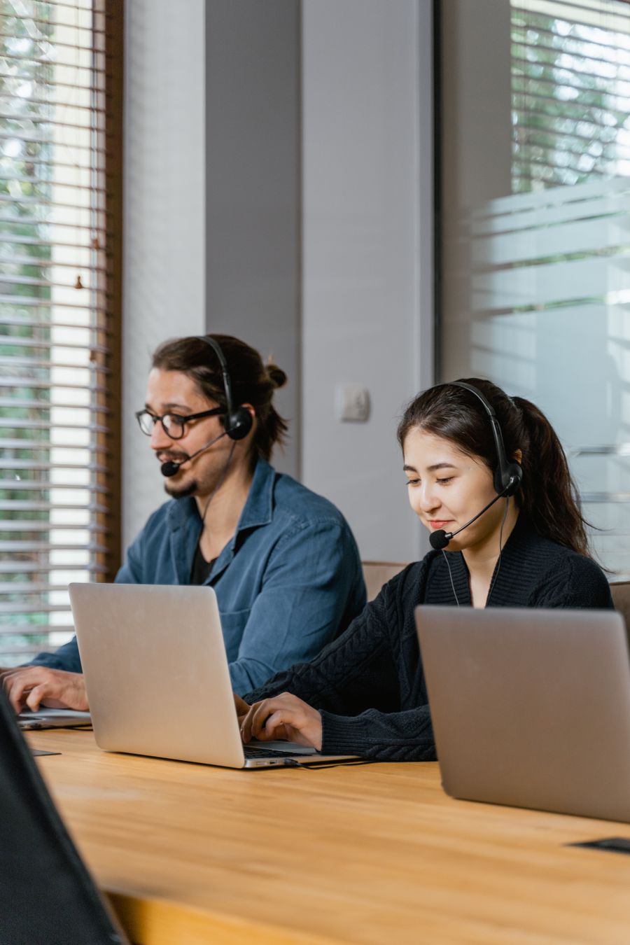 Two support agents working at laptops with headsets